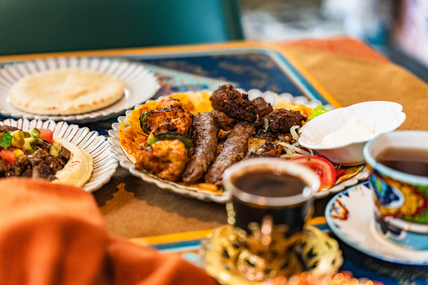 Gegrillte Spieße und Köfte auf einer Platte, dazu Fladenbrot und Tee